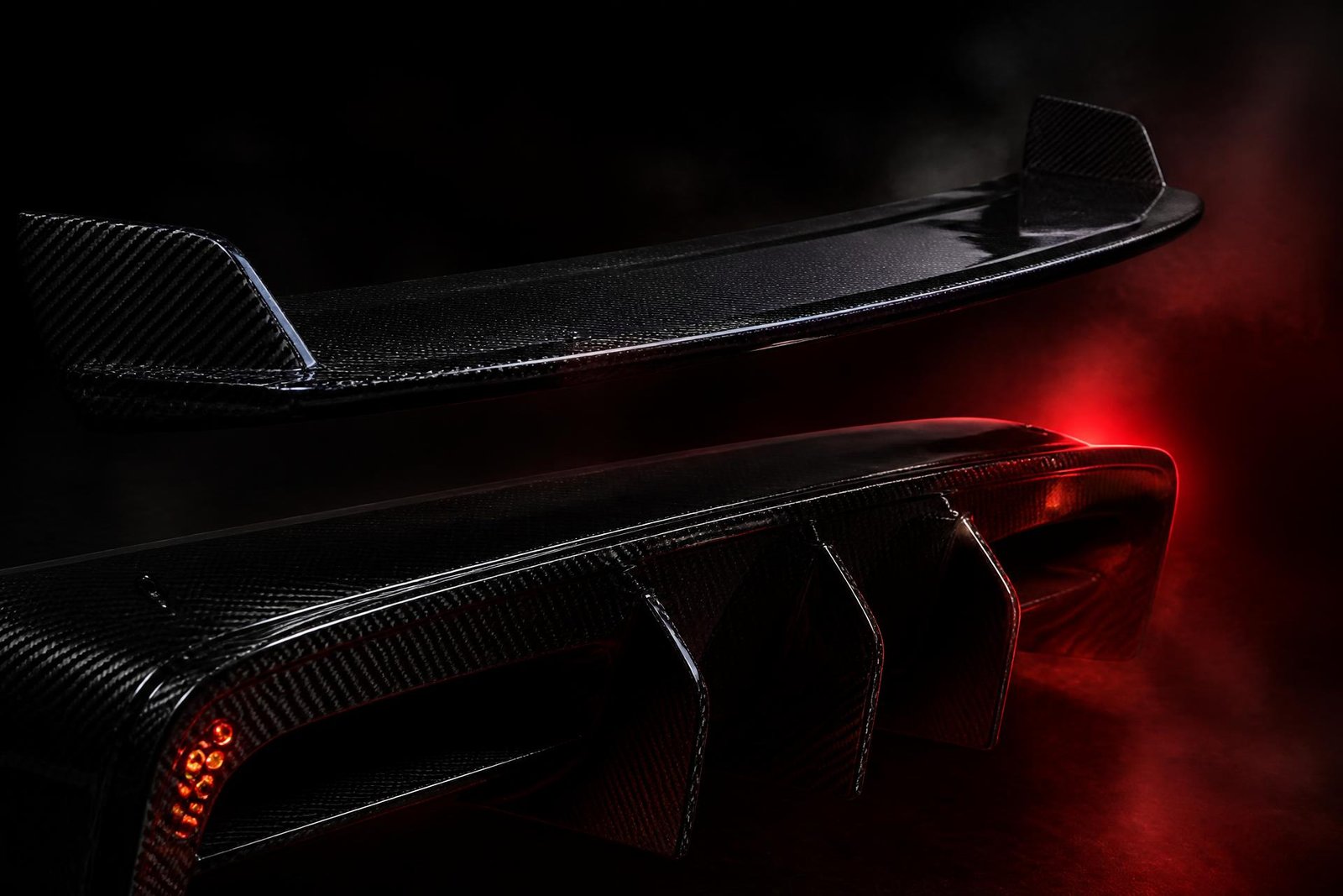 Carbon fiber supercar rear wing and diffuser under red studio lighting